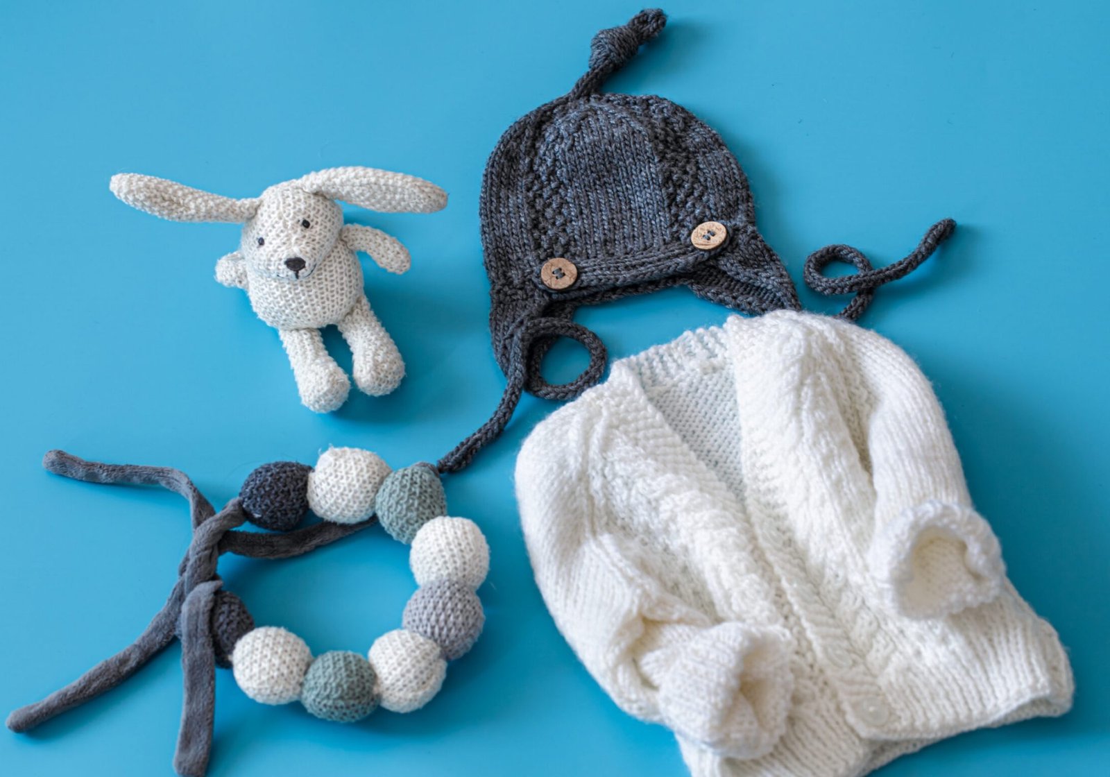 Knitted baby clothes and accessories on a blue background . The view from the top